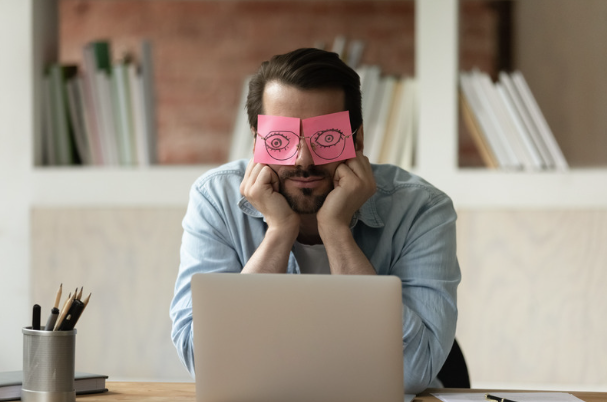 business man suffering from burnout with post-its over his eyelids to look awake