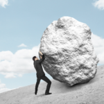 businessman pushing a large rock up a hill