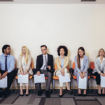 business people sitting and waiting with resumes to be interviewed