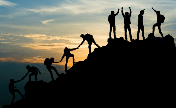 men helping others up the mountain