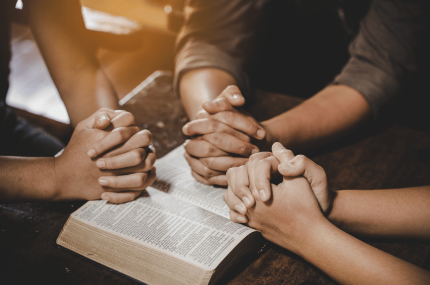 Spiritual People with praying hands over a bible